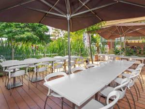 - un ensemble de tables et de chaises avec parasols sur la terrasse dans l'établissement ibis Medellin, à Medellín