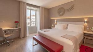 a hotel room with a large bed and a desk and a window at NH Collection Porto Batalha in Porto