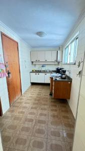 a large kitchen with white cabinets and a table at Apart temporada Rio de Janeiro in Rio de Janeiro