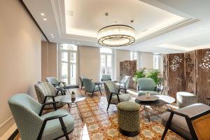 une salle d'attente avec des chaises, des tables et un lustre dans l'établissement Hôtel Apollinaire Nice, à Nice