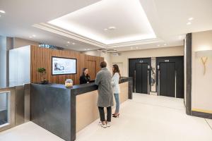 zwei Personen stehen an einer Theke in einer Lobby in der Unterkunft Hôtel Apollinaire Nice in Nizza