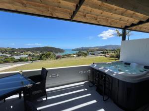 a hot tub on a balcony with a view of the ocean at Ranui Lodge in Mangonui