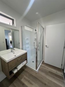 a white bathroom with a shower and a sink at Ranui Lodge in Mangonui