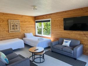 Habitación con 2 camas, sofá y TV. en Ranui Lodge, en Mangonui