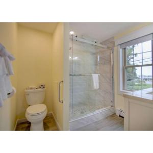 a bathroom with a toilet and a glass shower at Seacastles Resort in Ogunquit