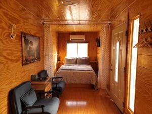 a bedroom with a bed and two chairs and a window at Sun Tiny House A Pahrump in Pahrump