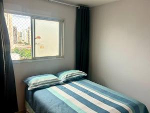 a bed with two pillows in a room with a window at Ap de 2 q, 70 metros, em bairro nobre e central in Goiânia