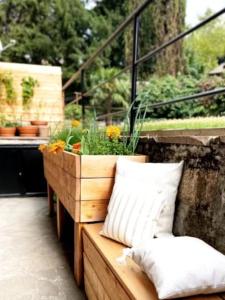 un banc en bois avec une plante en pot sur un balcon dans l'établissement Late Checkout Merano - 3 Zimmer, Sonnenterrasse, Garage, à Merano