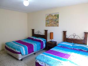 a bedroom with two beds and a picture on the wall at Hostal Los Volcanes in Guatemala