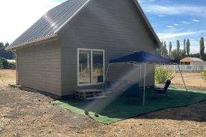 una casa con una sombrilla y dos sillas en una manta en Casa en salto del Laja, en El Manzano