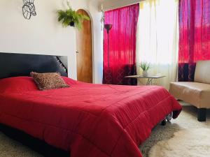 1 dormitorio con 1 cama roja y 1 silla en Hotel Boutique Tesoro, en Sevilla