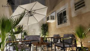 un patio con mesas, sillas y una sombrilla grande en Lenda House en Medina