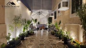 a patio with a table and an umbrella and potted plants at Lenda House in Al Madinah