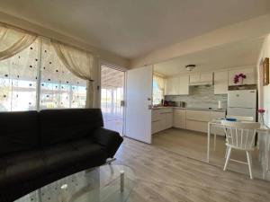 a living room with a black couch and a kitchen at Sun Tiny House B Pahrump in Pahrump