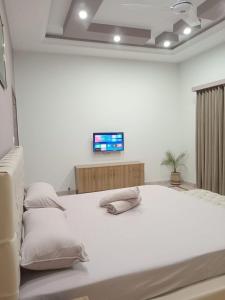 1 dormitorio blanco con 1 cama blanca grande con almohadas en COMFORT HOME en Gujrāt