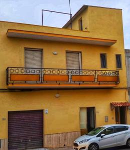 un edificio giallo con un'auto parcheggiata di fronte di Appartamento Ruffano a Ruffano