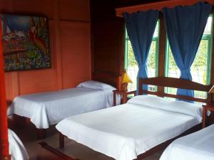 two beds in a room with blue curtains at El ocaso in Quimbaya