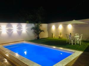uma piscina à noite com mesa e cadeiras em Casa com piscina exclusiva em Cabo Frio