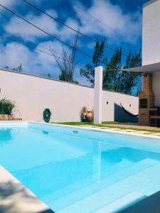 a swimming pool in front of a white wall at Casa com piscina exclusiva in Cabo Frio
