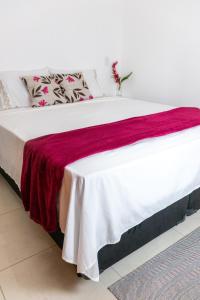 Una cama con una manta roja y blanca. en Suítes Margarida, en Ubatuba