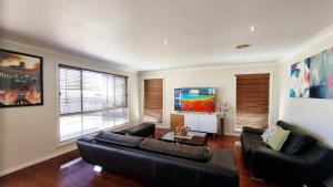 a living room with two leather couches and a tv at St Albans house - Spacious and modern home in St Albans