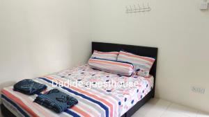 um quarto com uma cama com lençóis e almofadas coloridos em Dadide guesthouse em Kampong Alor Gajah