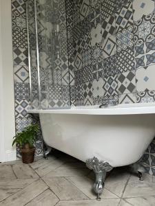 a white bath tub in a bathroom with a tiled wall at Ilford Tiny Jewel in Ilford