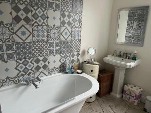 ein Badezimmer mit einer weißen Badewanne und einem Waschbecken in der Unterkunft Ilford Tiny Jewel in Ilford