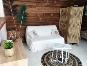 a living room with a white couch and a table at Studio Ti Kaye avec Jacuzzi in Les Trois-Îlets