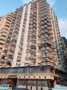 ein hohes Gebäude mit davor geparkt in der Unterkunft برج العزيزية بانوراما بحر للعائلات فقط in Alexandria