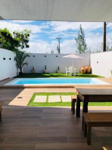 a swimming pool with a table and an umbrella at Casa com piscina exclusiva in Cabo Frio