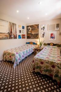 2 Betten in einem Zimmer mit Gemälden an den Wänden in der Unterkunft Casa de Arte CiTá, bed and breakfasts in San Miguel de Tucumán