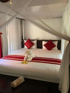 Una cama con almohadas rojas y un animal de peluche. en Teluk Karang Dive & Spa Resort en Tejakula