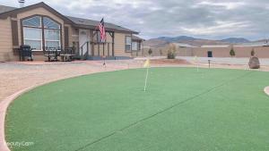 a putting green with a house and an american flag at Sun Cindy's House Pahrump in Pahrump