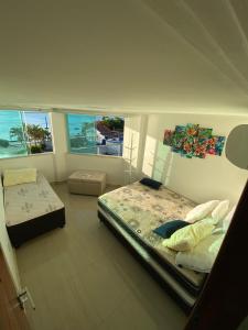 a bedroom with two beds and two windows at Triplex Curumim - Zohra in Itaparica