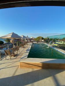a swimming pool with tables and chairs and umbrellas at Triplex Curumim - Zohra in Itaparica