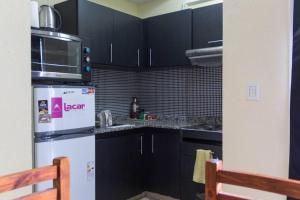 a kitchen with black cabinets and a white refrigerator at Monoambiente céntrico en San Miguel in San Miguel