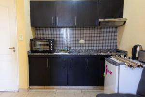 eine Küche mit schwarzen Schränken und einer Mikrowelle in der Unterkunft Bello departamento en San Miguel in General Sarmiento