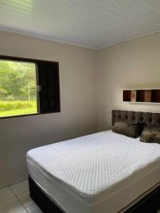un lit dans une chambre avec une fenêtre dans l'établissement Chácara Kamaleão, à Córrego do Bom Jesus 22 autres photos