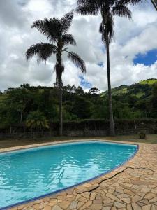 een zwembad met twee palmbomen op de achtergrond bij Casa de campo aconchegante in Córrego do Bom Jesus
