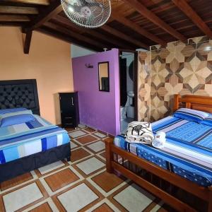 1 Schlafzimmer mit 2 Betten und einer lila Wand in der Unterkunft HOTEL CENTRAL TAMESIS in Támesis