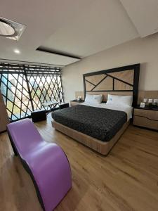 メキシコシティにあるHotel City Lightsの大きなベッドルーム(大型ベッド1台、紫のベンチ付)