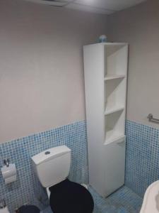 bagno con servizi igienici bianchi e parete piastrellata blu di Monoambiente en Muñiz a Muñiz