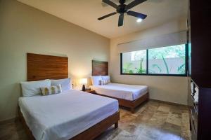 a bedroom with two beds and a ceiling fan at Zen Oasis Swim Up Condo Pool W Tiki Hut Bar + Gym in Tulum +17 photos