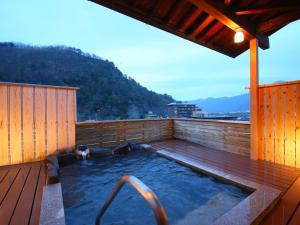 a hot tub on a deck with a dog in it at Ogiwarakan in Chikuma