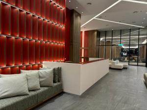 a lobby with a couch and a red wall at The Shore CBD Kota Kinabalu By LAXZONE SUITE in Kota Kinabalu