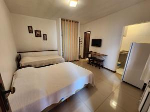 a hotel room with two beds and a desk at Pousada Bartrô in Rio das Ostras