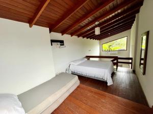 1 dormitorio con 2 camas y techo de madera en Jardim do Sol Residence, en Palhoça