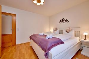 een slaapkamer met een groot wit bed met een paarse deken bij BergLiebe in Garmisch-Partenkirchen