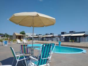 einen Tisch und Stühle mit einem Sonnenschirm neben einem Pool in der Unterkunft Casa do Lago - Pousada & Casas de Temporada in Penha